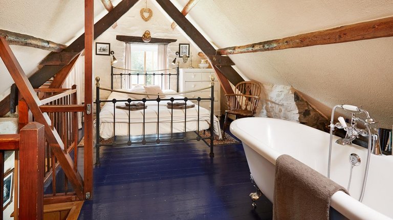 Freistehende Badewanne mit gemütlichem Doppelbett im walisischen Cottage