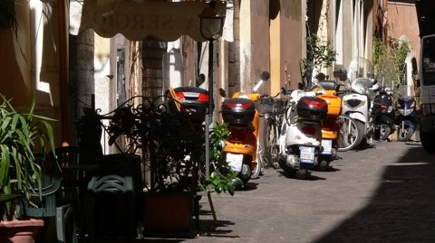 Kleine Straße mit bunten Vespas in Rom
