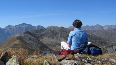 Frau sitzt mit Blick auf Südtiroler Panorama auf einem Stein