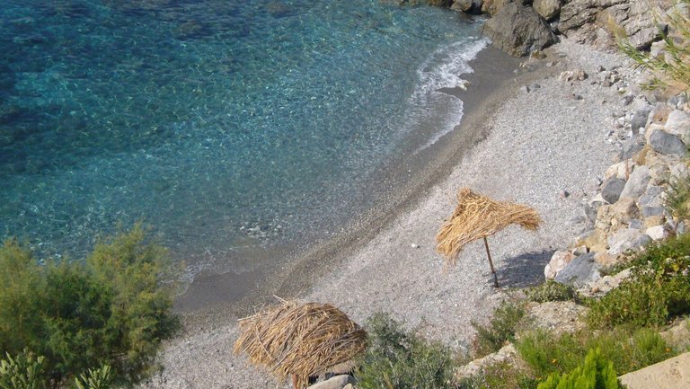 Spektakulärer Blick von oben auf Stroh-Sonnenschirme und Kieselstrand