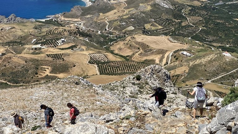 Wandergruppe läuft Berg hinab mit Blick auf die Küste