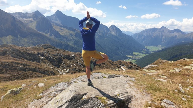 Frau, die Yoga macht, mit Blick auf ein Tal, das in Italien liegt