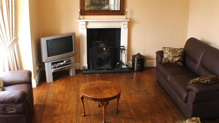 Wohnzimmer und offener Kamin mit Fernseher in walisischem Landhaus