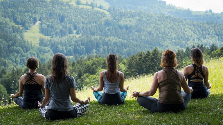 Ideal für Alleinreisende: Frauen machen Yin-Yoga mit Blick auf die Chiemgauer Berge