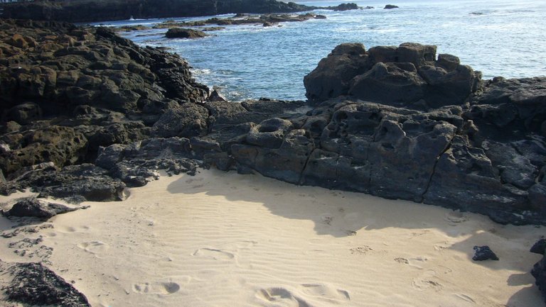 Vulkangestein umrahmt weisse Sandbuchten auf Lanzarote