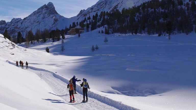 Alleinreisende Frauen mit Schneeschuhen vor Bergkulisse