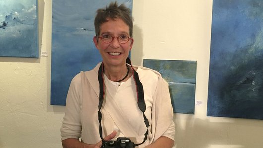 Elke Heinemann, Inhaberin von FRIdA Frauenreisen, mit Fotoapparat bei einer Ausstellung