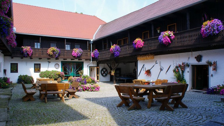 Innenhof mit Tischen und blühenden Balkonkästen unsereres Seminarhauses im östereichischen Mühlviertel